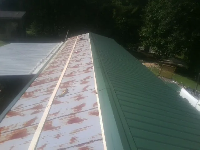 Old rusted panels beside newly installed green metal roofing — Wind Damage Roof Repair by Roofing Brothers in Monroeville
